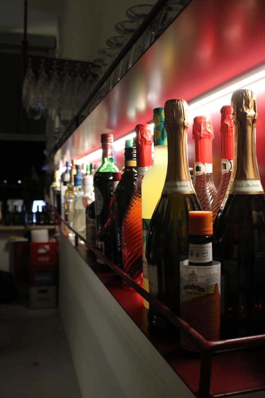 Bottles lined up along the red-lit back bar at Jazzin
